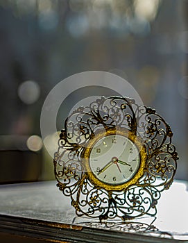 Vintage retro desk top clock with bokeh background. Clock is metal and has gold tones. photo