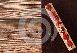 Scroll with seven seals and ancient key on top of closed holy bible book on wooden table