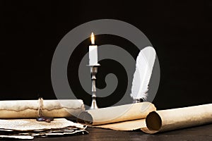 Scrolls of parchment and old papers on the background of a lit candle and inkwell pen