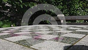 Scrubbed swirls of red spray paint mark the surface of a chess board table in a New York City park.