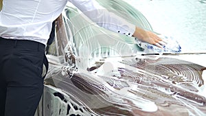 Scrupulous driver thoroughly washing windshield of his luxury car, carwash
