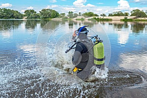 Scuba diver with equipment jumps in water with splashing