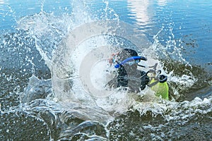 Scuba diver with equipment jumps in water with splashing