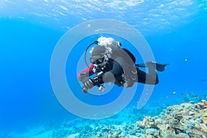 Scuba diver floating over coral reef.