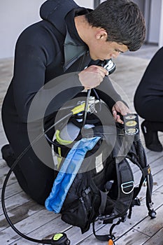 Scuba diver kitting up and checking his gear