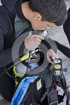 Scuba diver kitting up and checking his gear