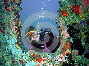 A Scuba Diver Peers Through a Coral-Encrusted Porthole