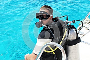 Scuba diver is preparing for diving into blue water from the boat. Underwater equipment