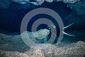 Scuba diver swims into an entrance into a underwater cave