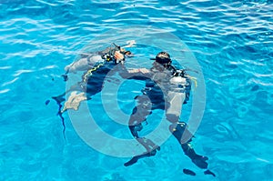 Scuba divers dive into the clear blue water in the sea