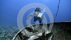 Scuba divers swimming explore shipwreck deep underwater.