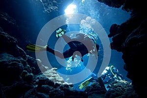 Scuba divers in underwater cave photo