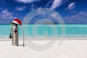 Scuba diving equipment with red Christmas hat on a tropical beach