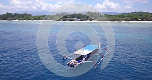 Scuba diving wooden boat floating over reef in tropical island sea, aerial