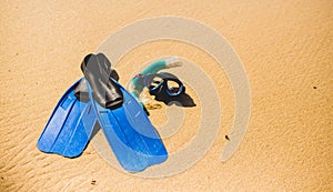 Scuba mask with flippers on the beach sand. Blue fins on the sandy beach