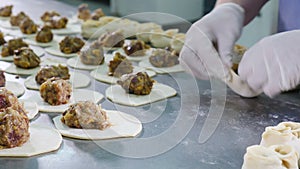 Sculpt dumplings. Women workers in white latex gloves wrap meat in dough for making dumplings. Meat factory. Close up