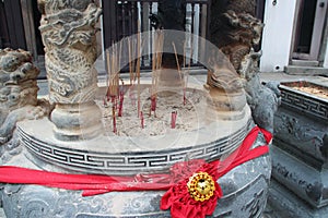 sculpted vase and incense sticks in a chinese temple (wak hai cheng bio) and modern buildings - singapore