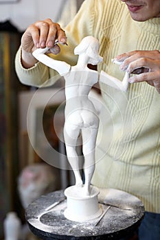 Sculptor attach arms to armless statuette. photo