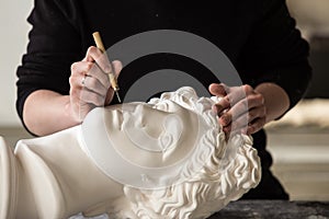 The sculptor conducts restoration work in a plaster workshop. Restoration of the gypsum head of Apollo