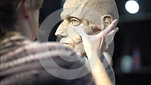 Sculptor creating sculpture of man's head. Woman working in studio. Cheekbones construction anatomy