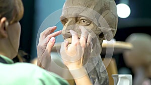 Sculptor creating sculpture of man's head. Woman working in studio. Nose construction anatomy