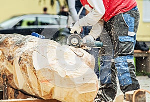 Sculptor work outddor with wooden blank and cutter