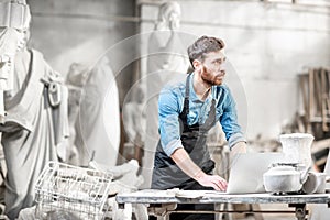 Sculptor working with laptop in the studio