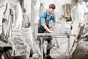 Sculptor working with laptop in the studio