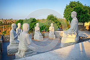 The sculptural composition of the Buddha and bodhisattva in the rays of sunset. Vietnam