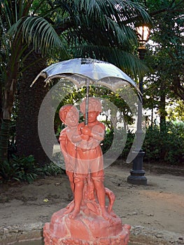 Sculpture of boy and girl with umbrella in the garden of Alameda Apodaca in Cadiz capital, Andalusia. Spain.