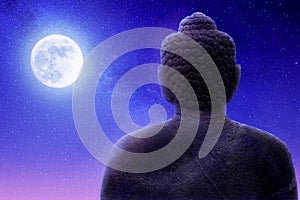 Sculpture of Buddha on a night sky background and moon. Artistic image.