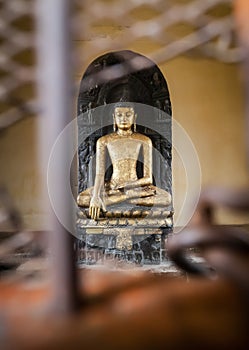 Sculpture of Buddha which is behind bars.