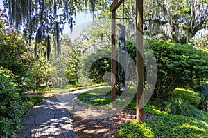 A sculpture called Travelin Light by Alison Saar with lush green trees, grass and plants and blue sky in Sculpture Garden