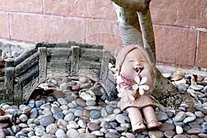 Sculpture clay girl with plumeria flower in the garden