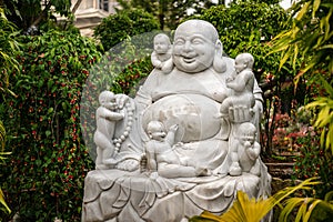 sculpture depicts a large white statue of Hotei sitting in the lotus position with small child on his lap. It is surrounded by