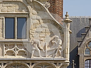 Sculpture of dockworkers, detil of an old guildhouse in Ghent