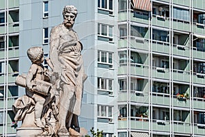 Sculpture of engineer and scholar on Zoll Bridge in Magdeburg and multistore building in background, Germany, contrast old and new