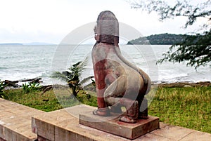 Sculpture of a fabulous red stone lion on the ocean