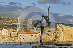 Sculpture girl dancing. Against the backdrop of the old town of Budva