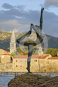 Sculpture girl dancing. Against the backdrop of the old town of Budva