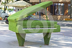 Sculpture of a grand piano with an open lid made of artificial grass, urban topiary