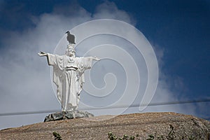 Sculpture of jesus christ with open arms with a vulture perched on his head