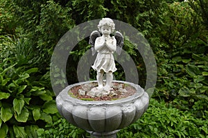 Sculpture of a little angel in the rain in the garden of the convent.