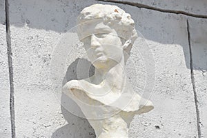 A sculpture of a mans head displayed against a white wall