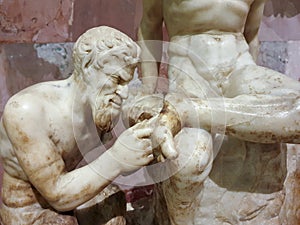 Sculpture of a naked man tickles the foot of another man