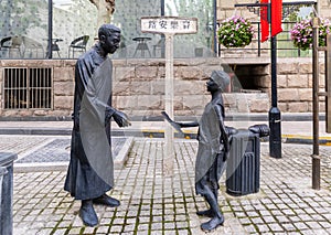 Sculpture of poor boy selling newspaper to man in traditional Chinese dress