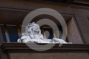 Sculpture of a reclining lion guarding a bag of money