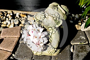 Sculpture thai girl doll with plumeria flower in the pebble garden