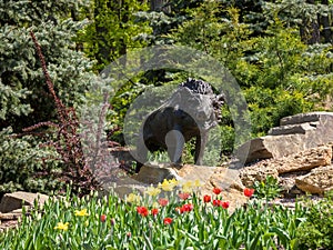 Sculpture of a wild boar on a stone, on a flower bed in the park