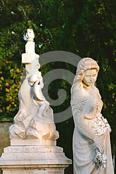 Sculpture of a woman at old cemetery. Close Up of stone figure and cross monument at cemetery. Old stone Graveyard statue on funer